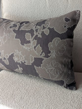 Cargar imagen en el visor de la galería, A rectangular lumbar throw pillow with a dark gray and taupe floral damask pattern, resting on a textured light gray sofa.